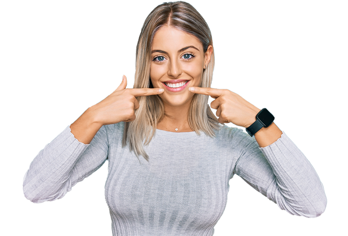 A smiling woman in a gray sweater points to her mouth. She wears a smartwatch, standing against a black background. Tone is happy and inviting.